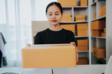 Asian small business owner working in home office with boxes, checking orders and preparing for delivery to customers. Online Marketing, SME Ecommerce Concepts