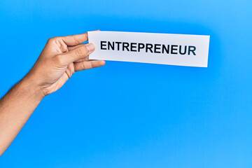 Hand of caucasian man holding paper with entrepreneur word over isolated blue background