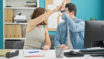 Two workers man and woman high five working at the office