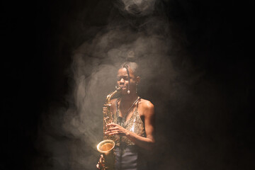 African American woman playing saxophone and performing jazz music with smoke on stage, copy space