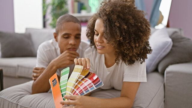 Beautiful couple lying on the sofa, smiling and looking around their home while enjoying the fun process of choosing the perfect paint color together