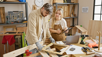 A man and woman team working together in a carpentry workshop, surrounded by woodcraft tools.