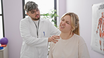 A male physiotherapist evaluates a woman's neck pain in a bright rehabilitation clinic.
