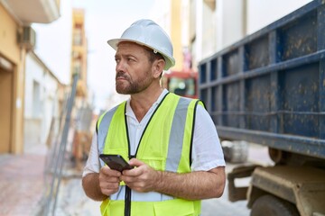 Middle age man architect using smartphone at street
