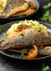 Pan fried sea bass fillets served with mashed potatoes and caramelised lemon