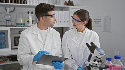 Fototapeta na wymiar Man and woman scientists discussing research in a laboratory, surrounded by equipment and samples.