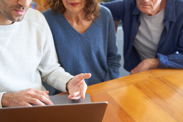 Male son teaching senior parents to  use laptop and coding