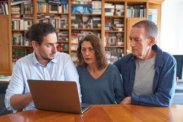 Male son teaching parents internet security on laptop