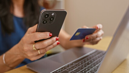 A businesswoman makes a secure online payment with her credit card and smartphone at her modern office workspace.