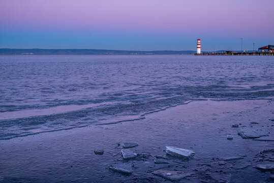 The frozen Neusiedler See with the lighthouse of Podersdorf in the background during a winter dawn in Burgenland, Austria.