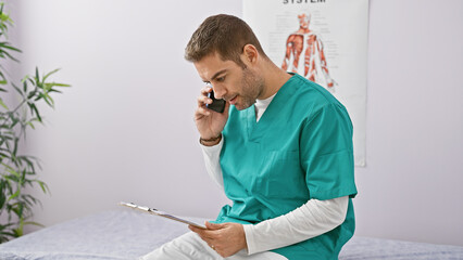 Hispanic male healthcare professional in scrubs multitasking with a clipboard and phone in a clinic...