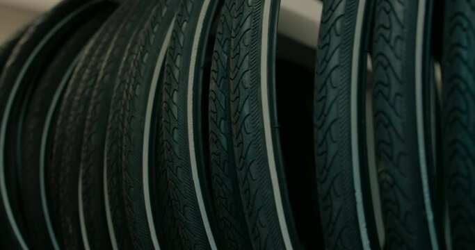 Bicycle tires lined up on wall of bike shop. 700 cc tires with reflective strip and threads for all terrain surface