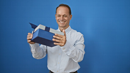 Middle age man smiling confident holding present over isolated white background