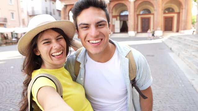 Beautiful young couple of lovers taking video selfie with smart mobile phone outside - Two happy tourists having fun visiting the city on summer vacation - Summertime holidays and technology concept