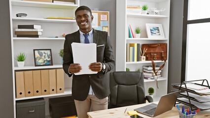 African american man smiling in office interior holding documents