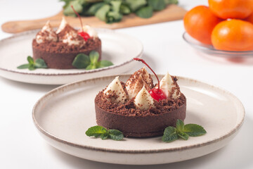 Fototapeta na wymiar Delicious chocolate tart garnish with cherry and mint. Classic dessert.