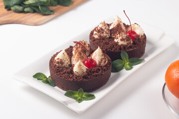 Fototapeta na wymiar Delicious chocolate tart garnish with cherry and mint. Classic dessert.