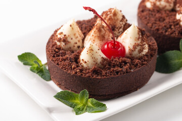 Delicious chocolate tart garnish with cherry and mint. Classic dessert.