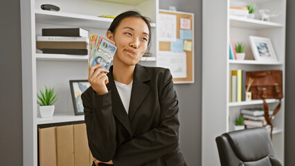 Asian woman holds australian dollars in modern office, hinting at finance, travel or business...