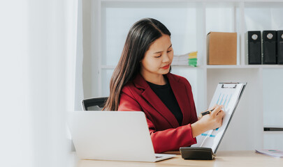 Asian businesswoman in a formal suit in the office with a laptop computer