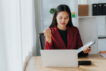 Asian businesswoman in a formal suit in the office with a laptop computer