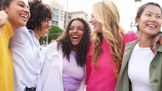 Multi ethnic group of young women hugging outside - Happy girlsfriends having fun laughing out loud on city street - Female community concept with cheerful girls standing together - 4k video