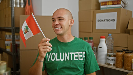 Young hispanic man volunteer smiling confident holding flag of peru at charity center