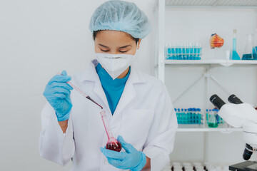 Female doctor taking blood sample tube from shelf with analyzer in lab Technician is holding blood test tubes in the laboratory.
