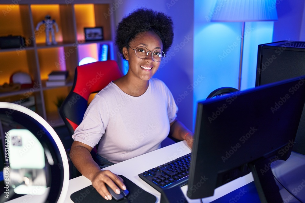 Poster African american woman streamer playing video game using computer at gaming room