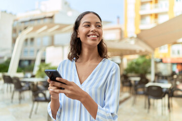 Young african american woman smiling confident using smartphone at coffee shop terrace