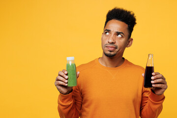 Young man wear casual clothes hold show juice green vegetable smoothie, bottle of soda pop look...