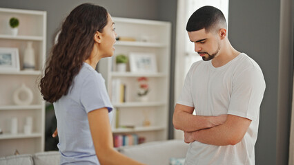 Fototapeta premium Serious argument at home, a beautiful couple locked in disagreement, standing together in their living room showcasing a lifestyle conflict.