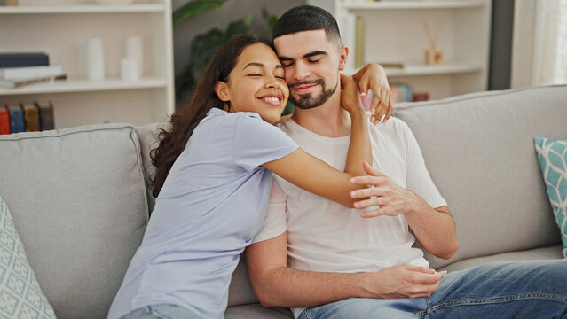 Beautiful couple's joyous moment, casually hugging, smiling, and enjoying life together on sofa at home