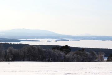 View of the mountains, meadows and the lake. Trees and mountains in winter. Winter landscape in Östersund.

