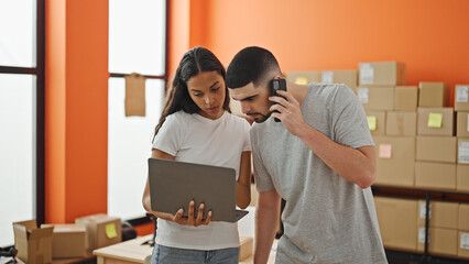 Two dedicated workers, a determined man and woman, tackling online business at the office, talking...