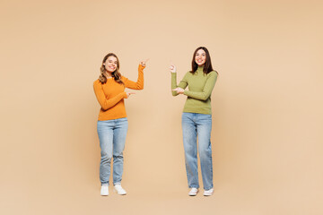 Full body young friends two women they wear orange green shirt casual clothes together point index...