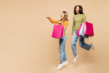 Full body young friends two women wear orange green shirt casual clothes hold shopping paper...