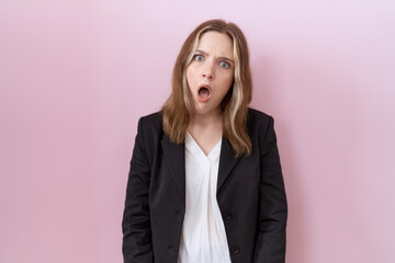Young caucasian business woman wearing black jacket in shock face, looking skeptical and sarcastic,...