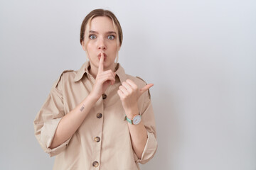 Young caucasian woman wearing casual shirt asking to be quiet with finger on lips pointing with hand to the side. silence and secret concept.