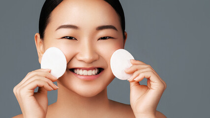 Skin cleansing. Face wash. Daily skincare. Beautiful korean young girl posing with a sponges. Beauty treatment and spa concept