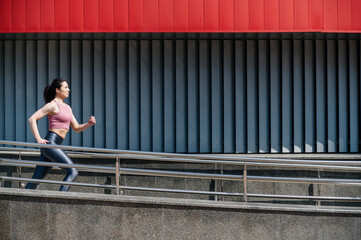 Side view shot of sporty athlete woman in activewear running outdoors