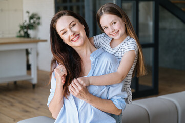 Happy woman and daughter spending time together, playing and resting in home