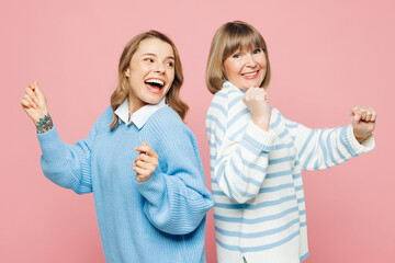 Elder happy parent mom 50s years old with young adult daughter two women together wear blue casual clothes dance having fun on party isolated on plain pastel light pink background. Family day concept. - obrazy, fototapety, plakaty