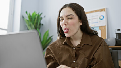 Young caucasian woman making a playful face in a modern office setting, depicting casual workday life.