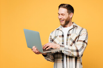 Young smiling happy smart Caucasian IT man wear brown shirt casual clothes hold use work on laptop...