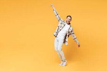 Fototapeta na wymiar Full body side view young Caucasian man wear brown shirt casual clothes stand on toes with outstretched hands leaning back isolated on plain yellow orange background studio portrait Lifestyle concept