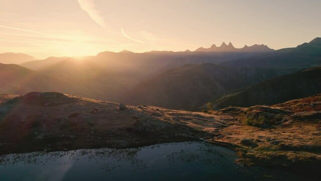 Sunrise shines over Lac Guichard with Arves massif and lake reflection in autumn at Aiguilles d'Arves, French Alps, France