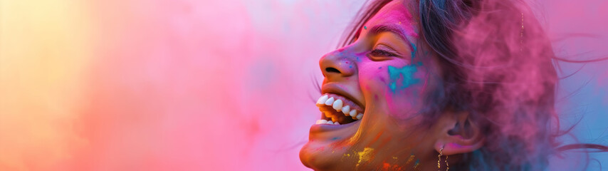 An Indian woman laughing joyfully with her face covered in vibrant colored powder. Holi Festival,...