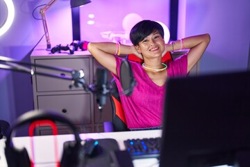 Fototapeta na wymiar Middle age chinese woman streamer smiling confident relaxed with hands on head at gaming room