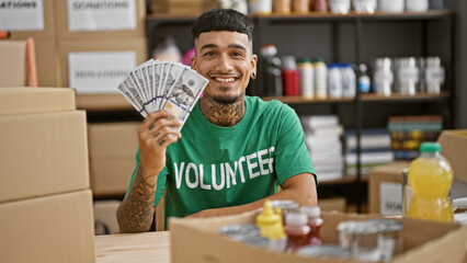 Handsome, tattooed young latin man, smiling confidently, volunteering at the charity center,...